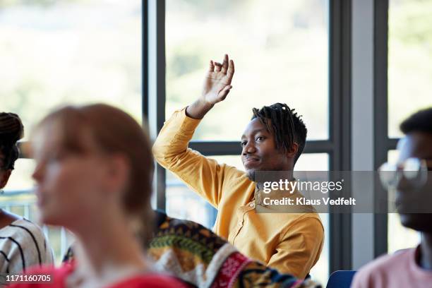 confident student looking away with arm raised - questions and answers stockfoto's en -beelden