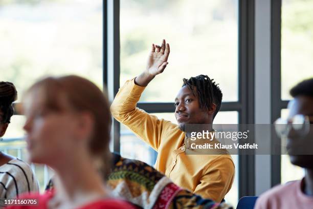 confident student looking away with arm raised - q and a stock pictures, royalty-free photos & images