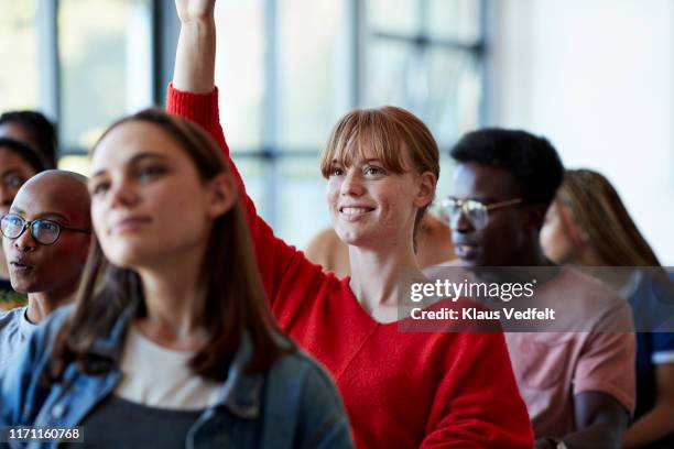 smiling young woman raising arm in classroom - participant fotografías e imágenes de stock