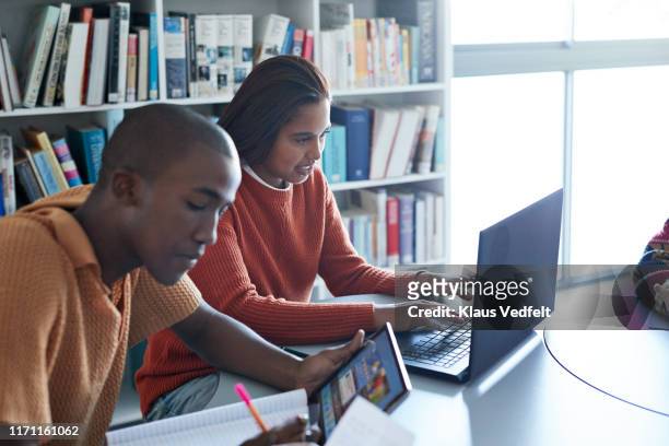 Woman using laptop by friend studying at desk
