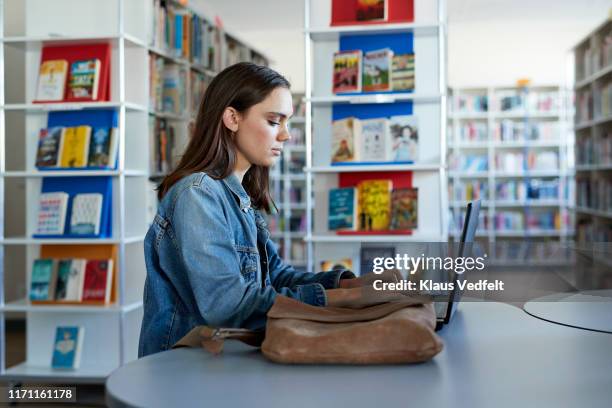 confident female student using laptop at desk - student sitting in desk side view stock pictures, royalty-free photos & images