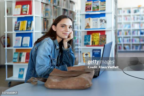 confident young female student sitting at desk - generation z laptop stock pictures, royalty-free photos & images