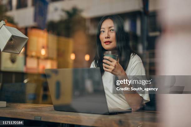 young woman working on laptop in cafe - contemplation woman stock pictures, royalty-free photos & images