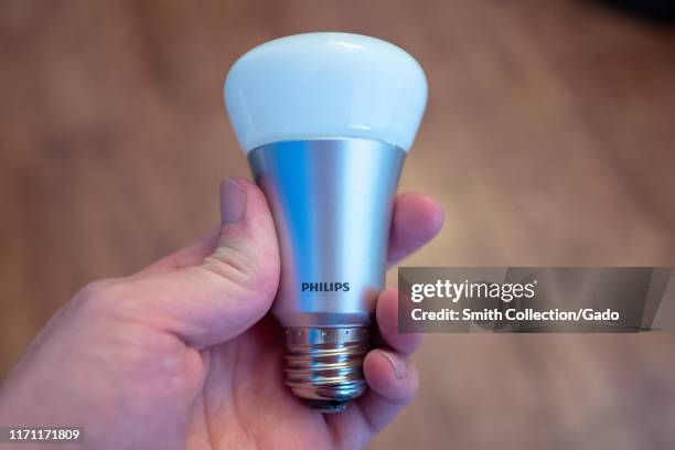 Close-up of hand of a man holding a Philips Hue web-connected smart lightbulb, August 29, 2019.