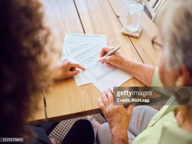 senior woman signing documents in her home - signing paperwork stock pictures, royalty-free photos & images