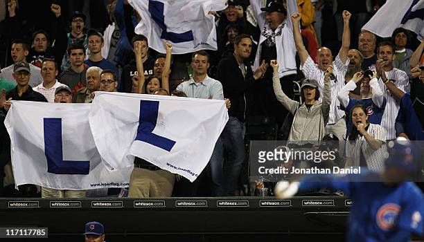 Fans of the Chicago White Sox hold "L" flags, flown at Wrigley Field when the Chicago Cubs lose, as Carlos Pena of the Cubs strikes out to end the...