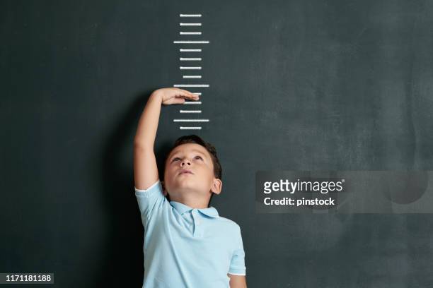 niño midiendo su altura en la pared. está creciendo tan rápido. - kid with markers fotografías e imágenes de stock