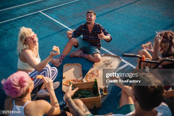 alternative friends eating pizza and drinking beer while telling stories - pizza humour stock pictures, royalty-free photos & images