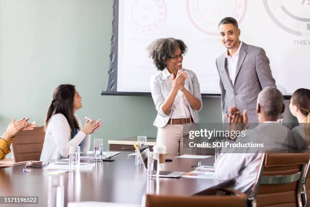 mature businesswoman introduces guest during meeting - guest speaker stock pictures, royalty-free photos & images