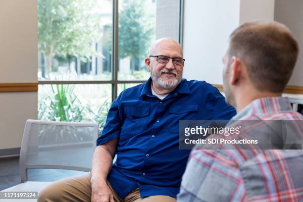 mature adult father listens attentively to unrecognizable mid adult son - group of mature men stock pictures, royalty-free photos & images
