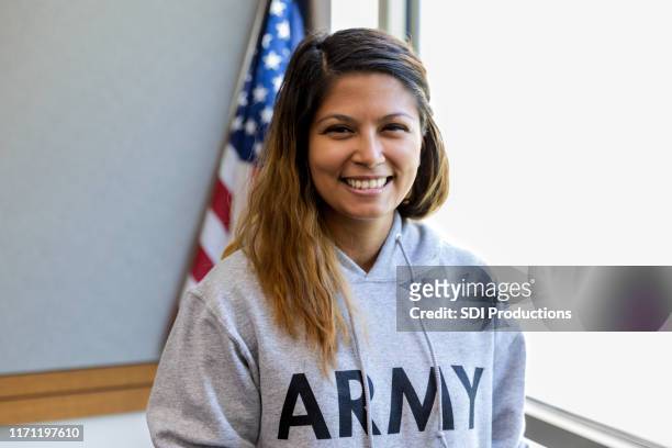 female veteran with big smile in front of american flag - army woman stock pictures, royalty-free photos & images