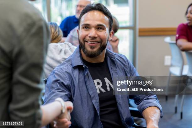 army veteran in wheelchair shakes hands with unrecognizable woman. - male group therapy stock pictures, royalty-free photos & images