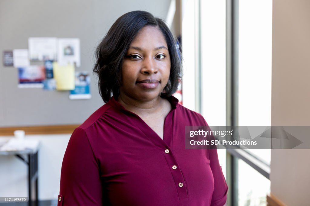 Mid adult teacher poses for portrait in classroom