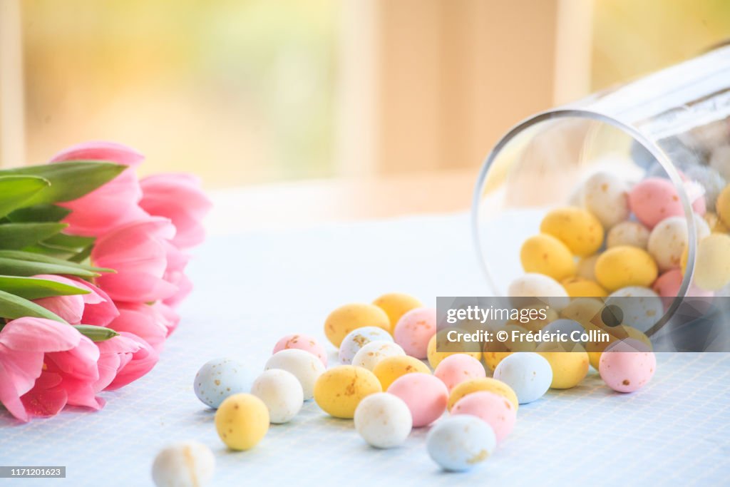Easter eggs fallen from a glass jar and tulips bouquet