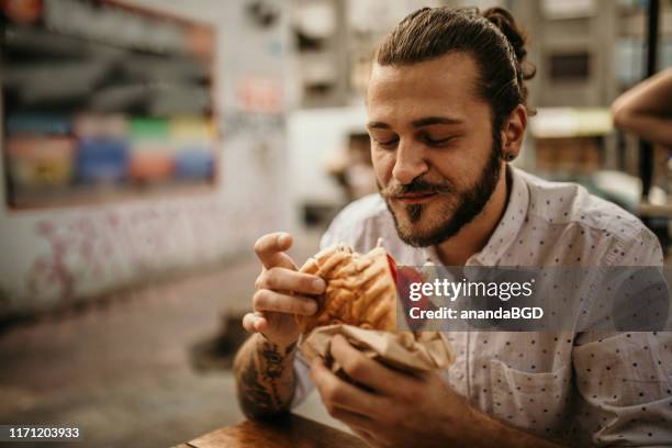 street food - man holding a burger stock pictures, royalty-free photos & images