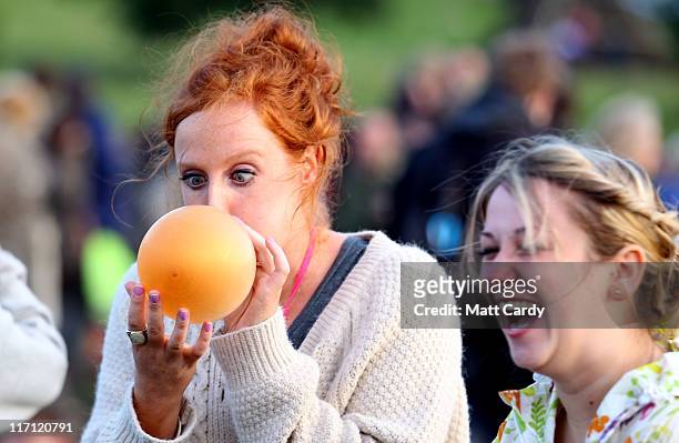 Girl blows into a balloon at the Stone Circle as people gather to see the sun set at the Glastonbury Festival site at Worthy Farm, Pilton on June 22,...