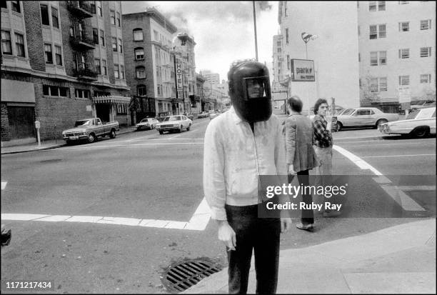 American film director and screenwriter Amos Poe wearing a welding helmet on the streets of the Tenderloin neighbourhood of downtown San Francisco,...