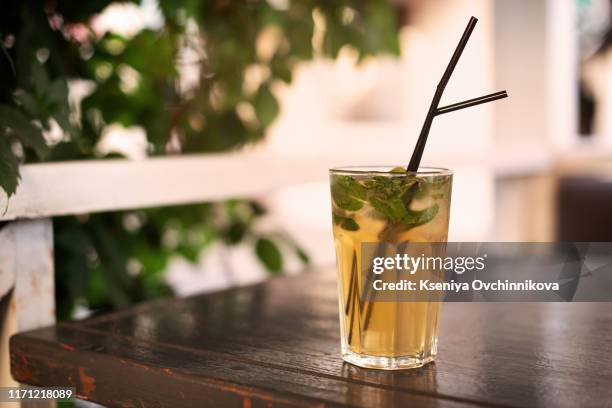 low angle close up of ice cold modern gourmet craft cocktail of gin and tonic soda garnished by lemon slice and rosemary sprig sprinkled by juniper berries on bar with blurry restaurant bar background - juniper berries stock pictures, royalty-free photos & images