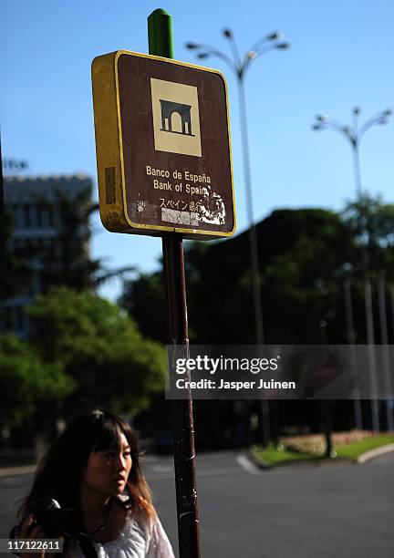 Tourist holds on to her camera as she passes a Bank of Spain sign on June 23, 2011 in Madrid, Spain. Eurozone finance ministers are currently seeking...