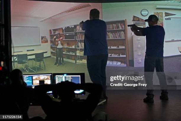 Utah teachers interact with a video simulator that creates an active shooter scenario in a school during a training session on September 25, 2019 in...