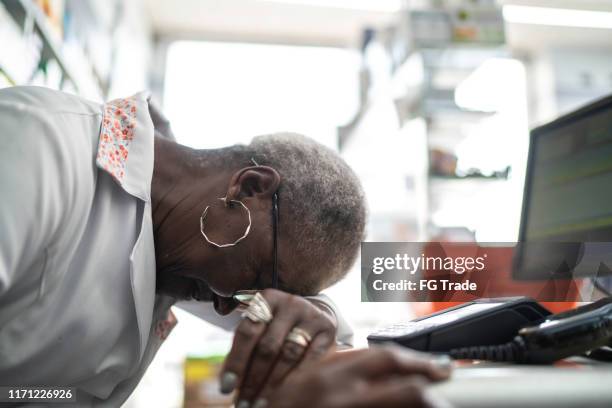 frustrated senior pharmacist with head down in front of a computer - black pharmacist stock pictures, royalty-free photos & images