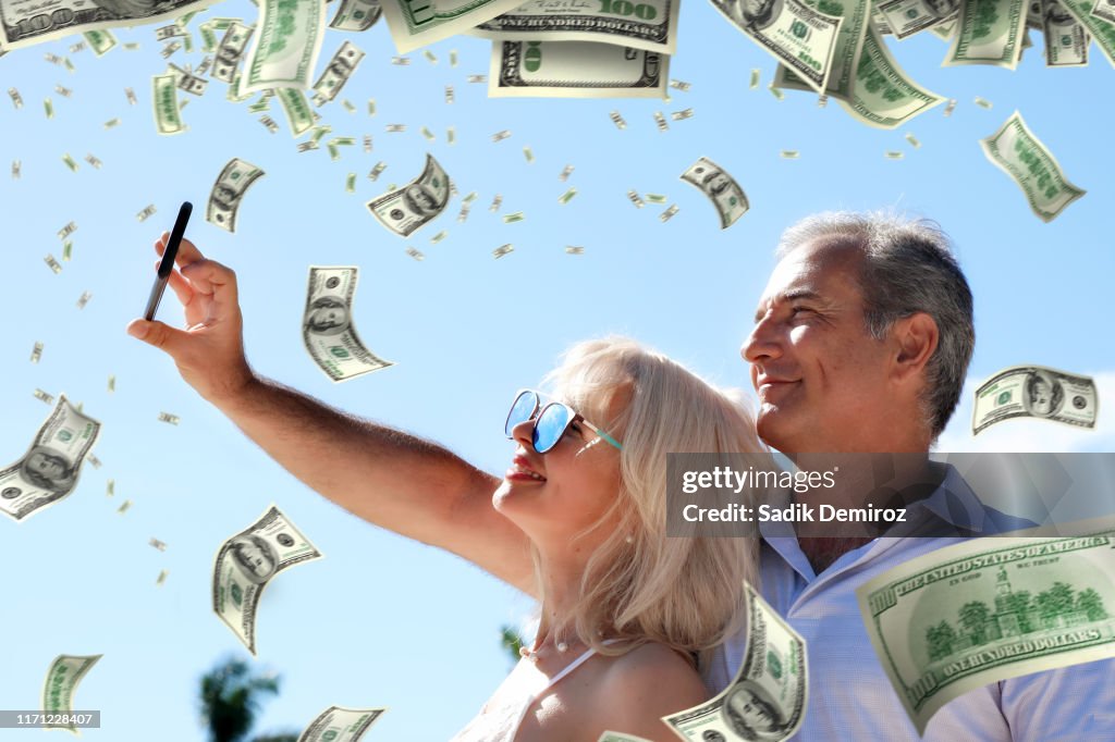 Portrait middle age adult couple and falling large group of money