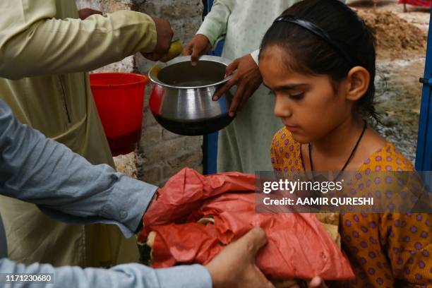 Pakistani men distribute food aid to a young girl in an earthquake-hit area on the outskirts of Mirpur in Pakistan-controlled Kashmir on September...