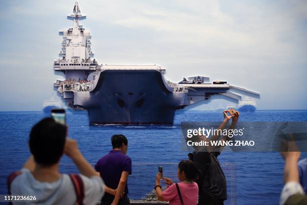Group of people take pictures of a model of the aircraft carrier Liaoning at an exhibition marking China's achievements over the past 70 years, ahead...
