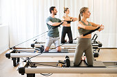 Three people exercising torson rotation at gym
