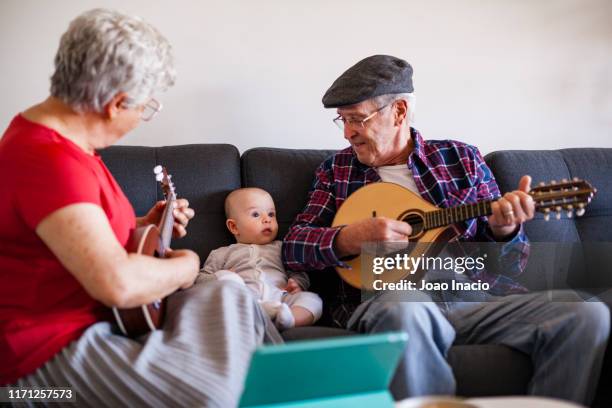 senior couple playing music for baby - disruptaging stock pictures, royalty-free photos & images
