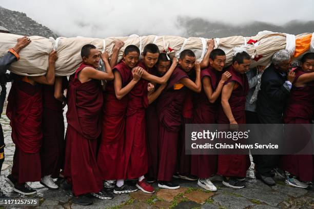 Tibetan Buddhist monks carry a giant thangka to display during the Sho Dun Festival at Drepung Monastery on August 30, 2019 in Lhasa, Tibet...