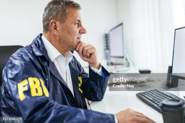 agente fbi che utilizza il computer in ufficio - fbi agents foto e immagini stock