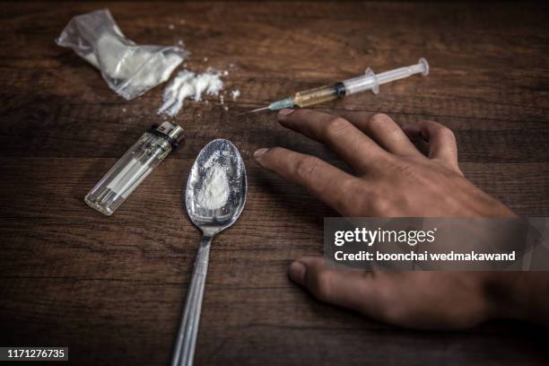 unconscious drug addict hands lying on grungy concrete floor with pills, syringe, cooked heroine. dangers of drug addict and abuse concept. international day against drug abuse. - drogados imagens e fotografias de stock
