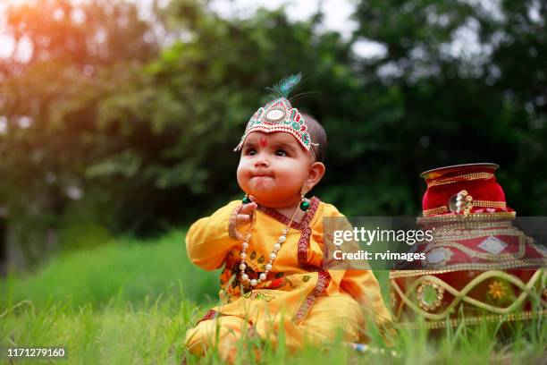 kleine krishna sitzt mit makhan matki - hindu god krishna stock-fotos und bilder