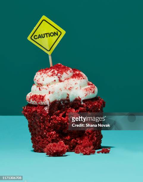 half eaten cupcake with caution sign - food safety stock-fotos und bilder
