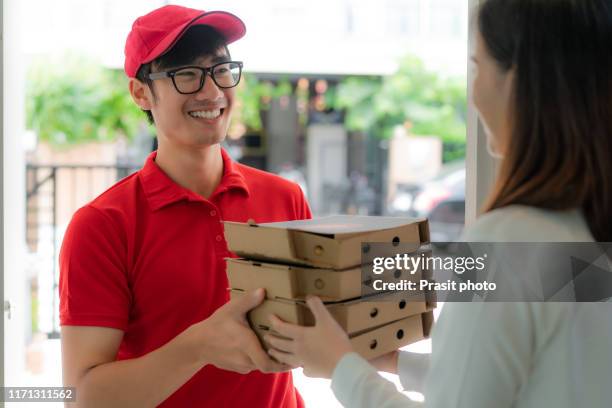 asian man delivering pizza food in paper boxes to asian woman customer at home. - pizza delivery stock pictures, royalty-free photos & images