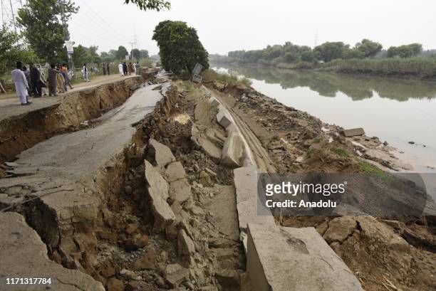 People walk near a badly damaged road days after a powerful earthquake with magnitude of 5.8 hit the area in Jatlan town in the Mirpur District in...
