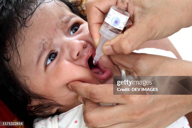 administering oral poliovirus vaccine to newborn baby - polio virus stockfoto's en -beelden