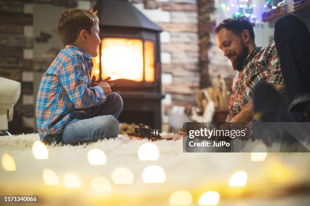 father and son enjoying christmas holidays at home - game night stock pictures, royalty-free photos & images