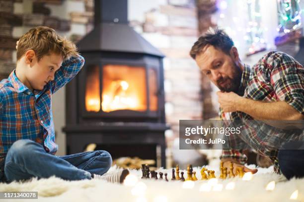 father and son enjoying christmas holidays at home - game night stock pictures, royalty-free photos & images