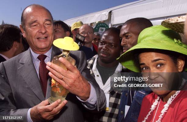 Le président de la République Jacques Chirac, tient une bouteille de rhum de l'ile de la Réunion offerte par des agriculteurs, le 16 septembre 1999,...