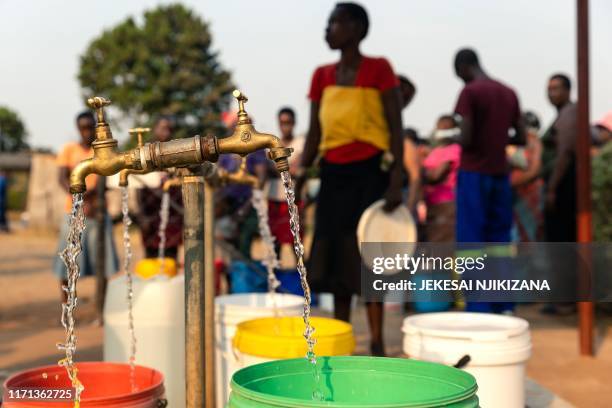 People queue to collect bucket loads of water from a borehole drilled by Non Governmental Organisations in Glen View Township as municipal water is...