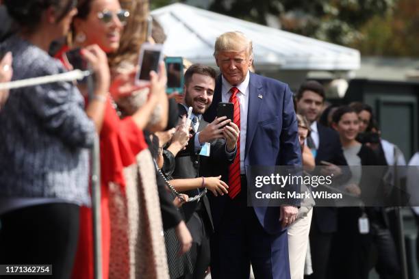 President Donald Trump takes a photo with an onlooker as he returns to the White House after attending the United Nations General Assembly on...