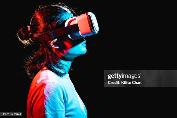 woman using virtual reality headset at night - realidad virtual fotografías e imágenes de stock