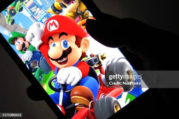 Woman shows the title Mario Kart Tour on her smartphone during game center in Tokyo, Japan September 26, 2019. After over a year of waiting Mario...