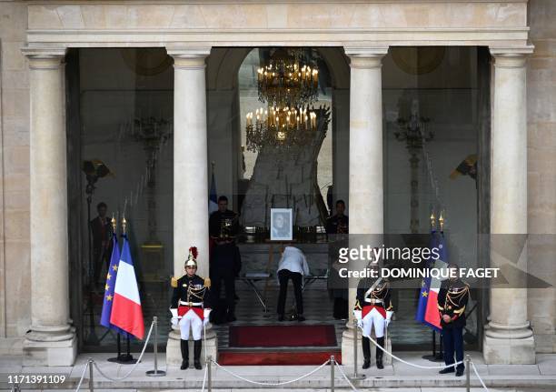 Republican guards stand next to a portrait of Jacques Chirac displayed at the Elysee presidential palace in Paris on September 27, 2019 as French...