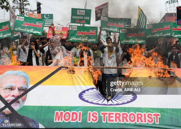 Activists of the "Youth Forum for Kashmir" group shout slogans as they burn a banner representing India's Prime Minister Narendra Modi and the Indian...