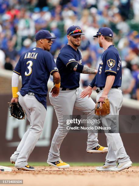 Orlando Arcia, Yasmani Grandal and Cory Spangenberg of the Milwaukee Brewers celebrate the end of their team's 2-0 win over the Chicago Cubs at...