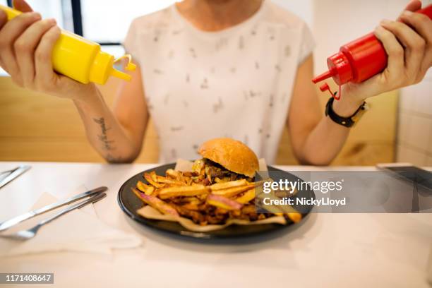 adicionando alguma especiaria a seu prato - cheesburguer - fotografias e filmes do acervo