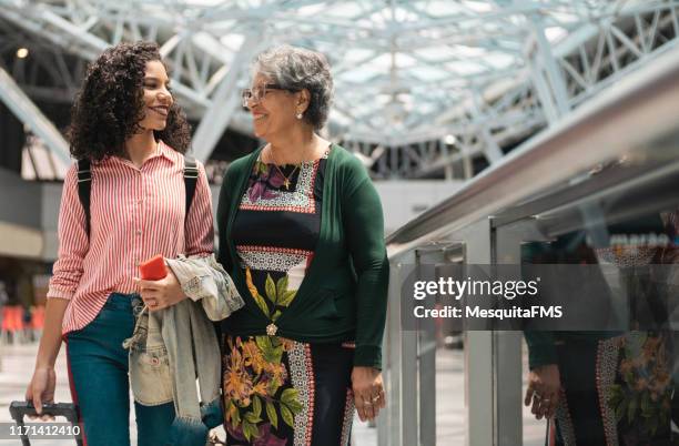 grandmother and her granddaughter waiting for the flight time at the airport - family mall stock pictures, royalty-free photos & images